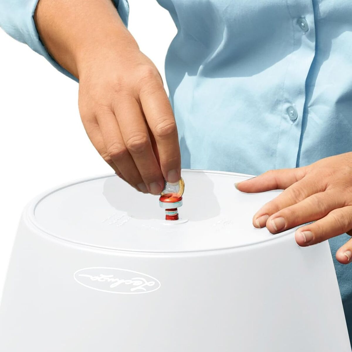 Personne insérant une pièce dans un pot Lechuza blanc.
