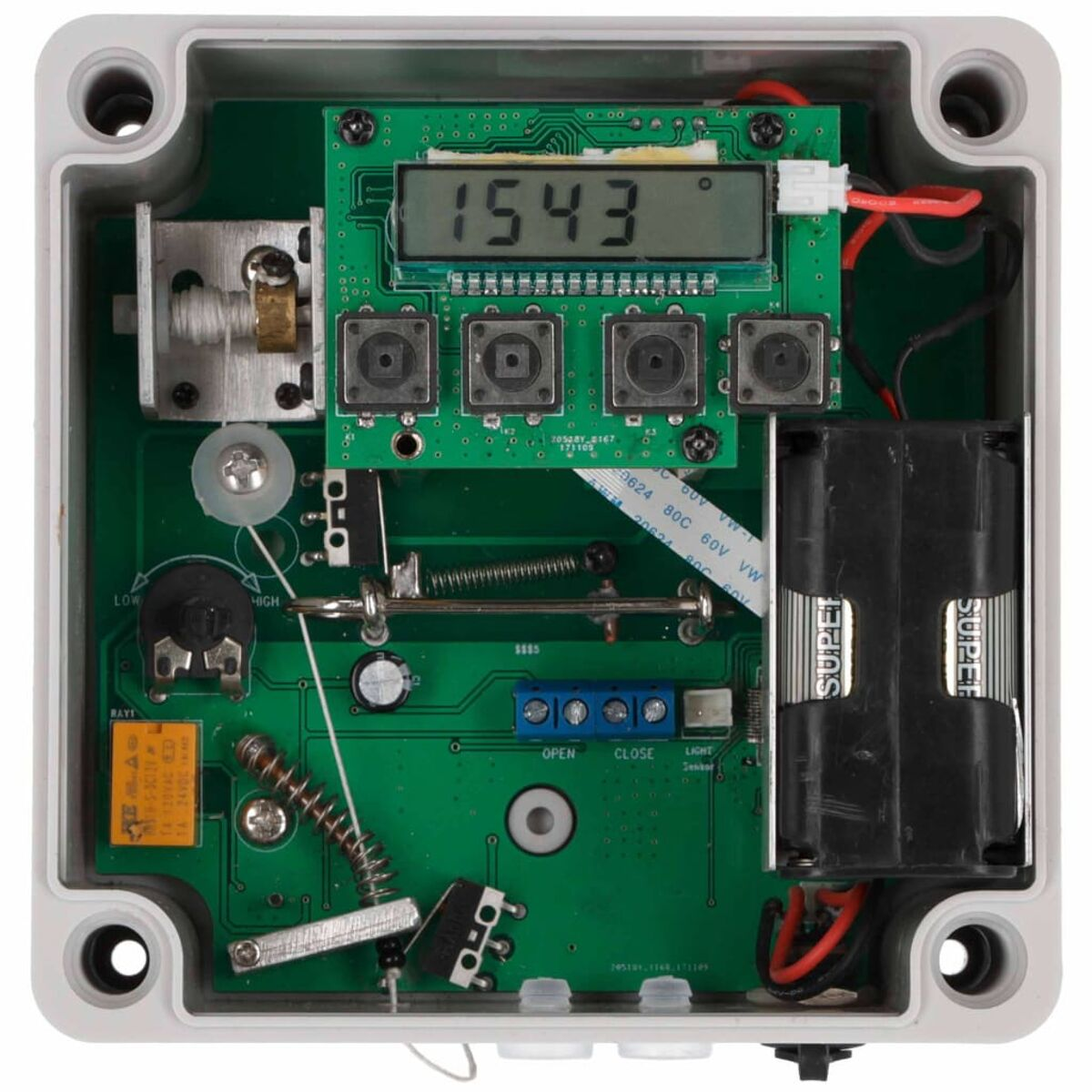 Dispositivo electrónico abierto mostrando placa de circuito, botones, pantalla, batería y cableado.