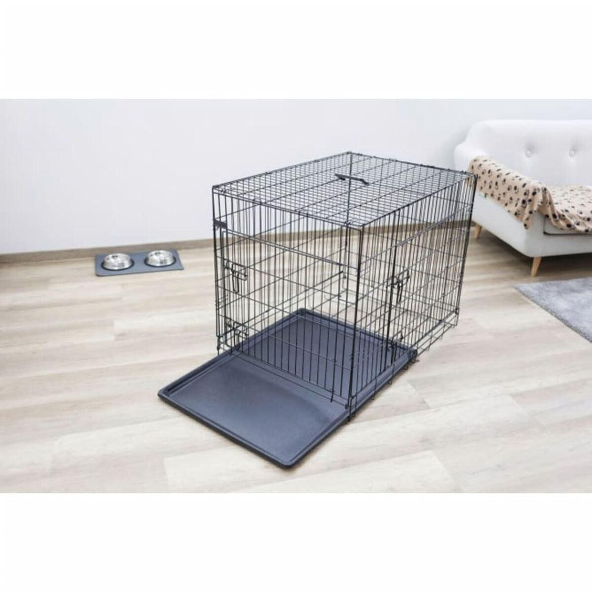 Schwarze Draht-Hundebox mit offener Tür, Metallschüsseln an der Seite, drinnen.