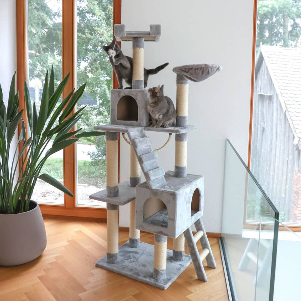 Katzenbaum mit zwei Katzen. Eine Katze ist auf der obersten Ebene, die andere auf der mittleren Ebene.