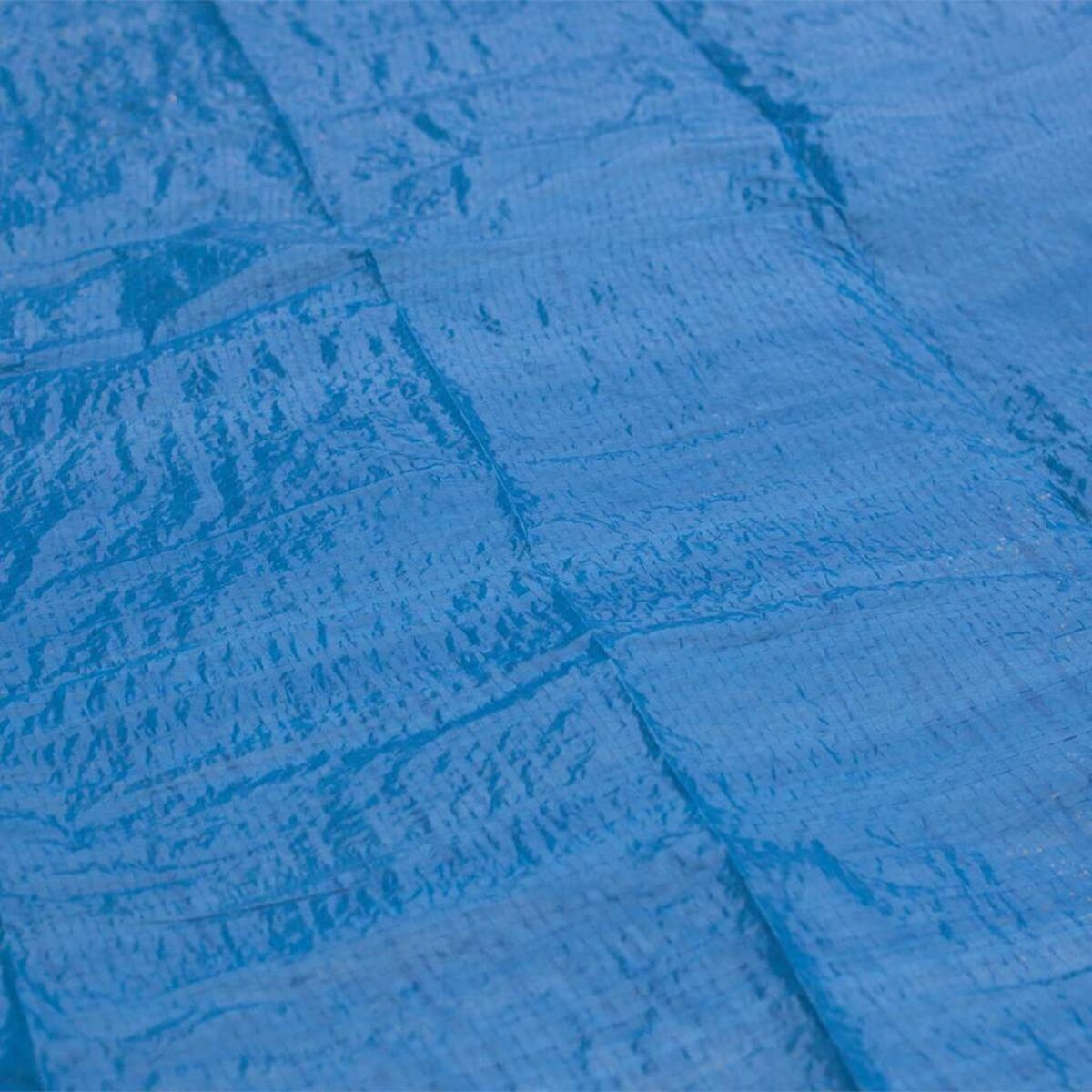 Nahaufnahme einer blauen Plane mit strukturierter Oberfläche. Das Material ist gefaltet.