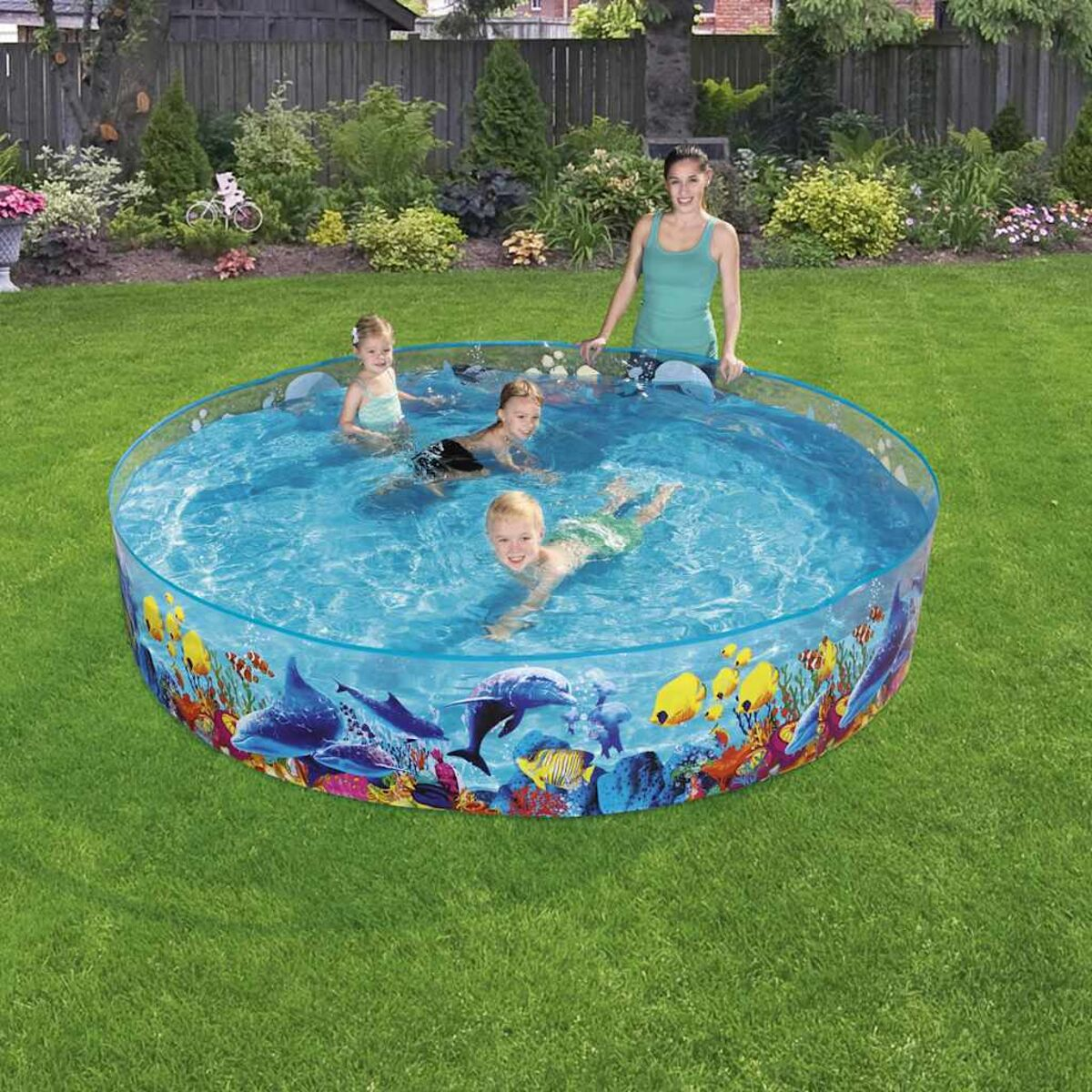 Vier Kinder und eine Frau in einem Pool mit farbenfrohem Meeresmuster am Rand.
