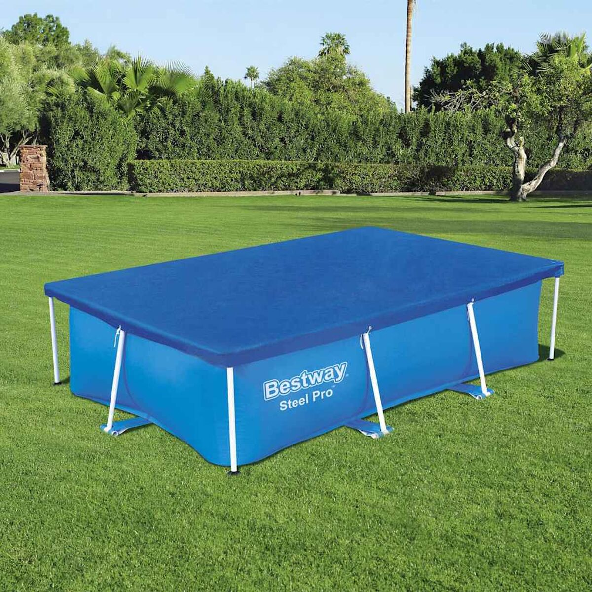 Blauer, rechteckiger Pool mit blauer Abdeckung auf grünem Gras, Bäume im Hintergrund.
