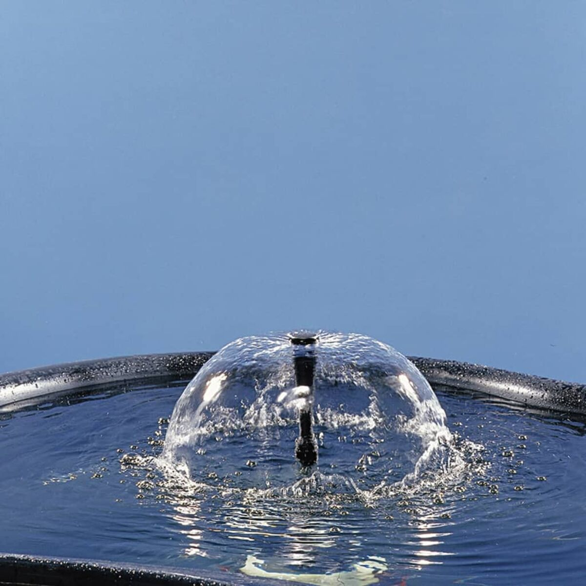 Ein Wasserbrunnen mit einer Wasserkuppel vor blauem Hintergrund.
