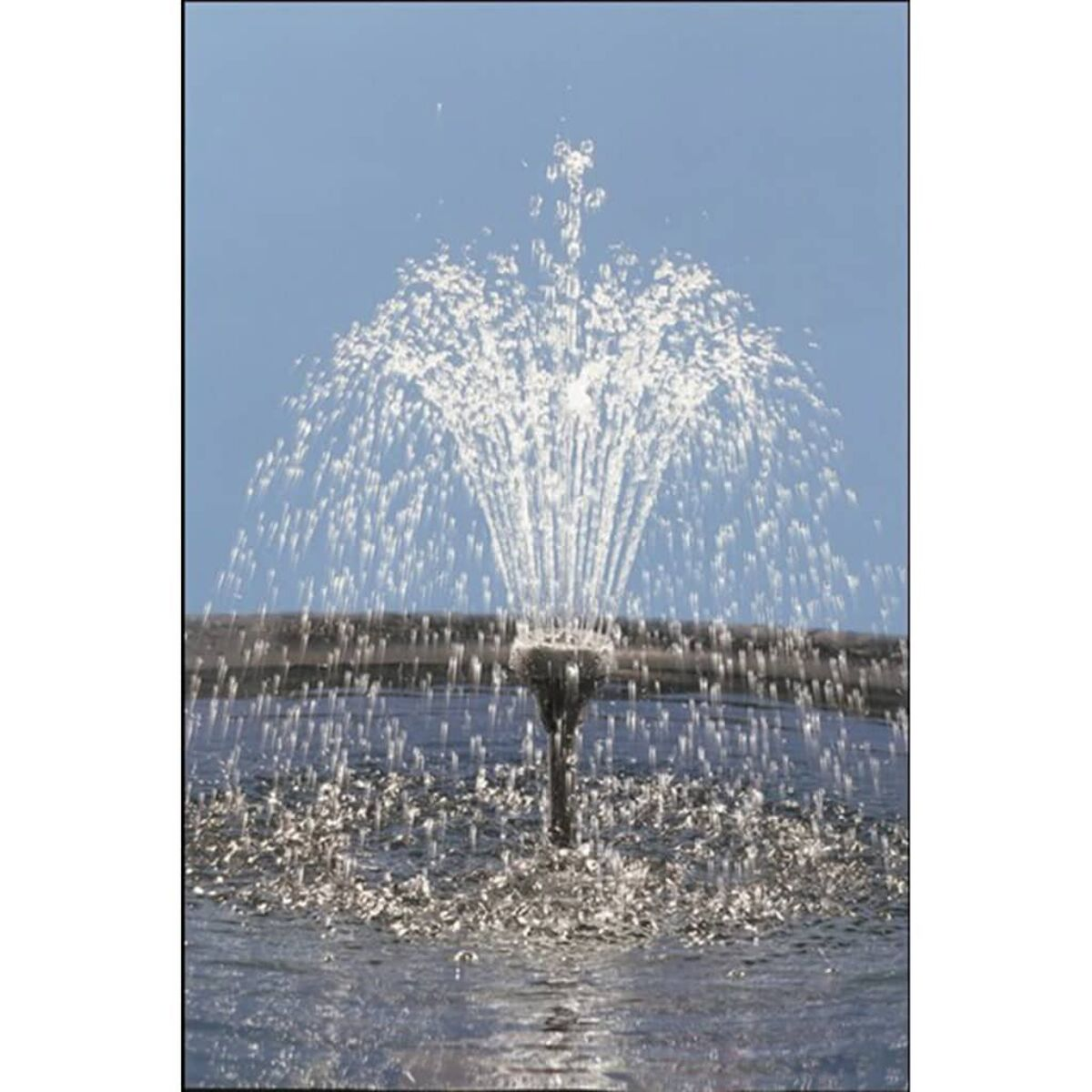 Ein Springbrunnen spritzt Wasser hoch in die Luft vor blauem Himmel.