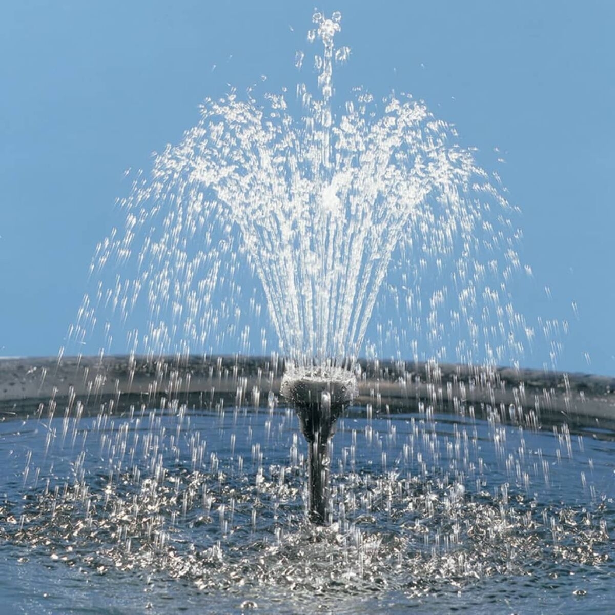 Ein Wasserbrunnen spritzt Wasser nach oben vor einem blauen Himmel.