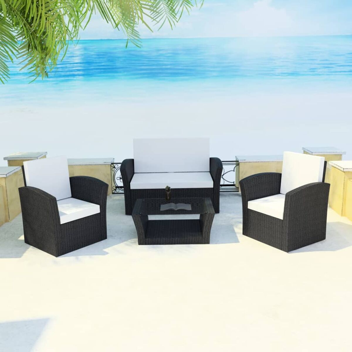 Terrassenset mit schwarzen Korbmöbeln, weißen Kissen und einem Glastisch, Meer im Hintergrund.