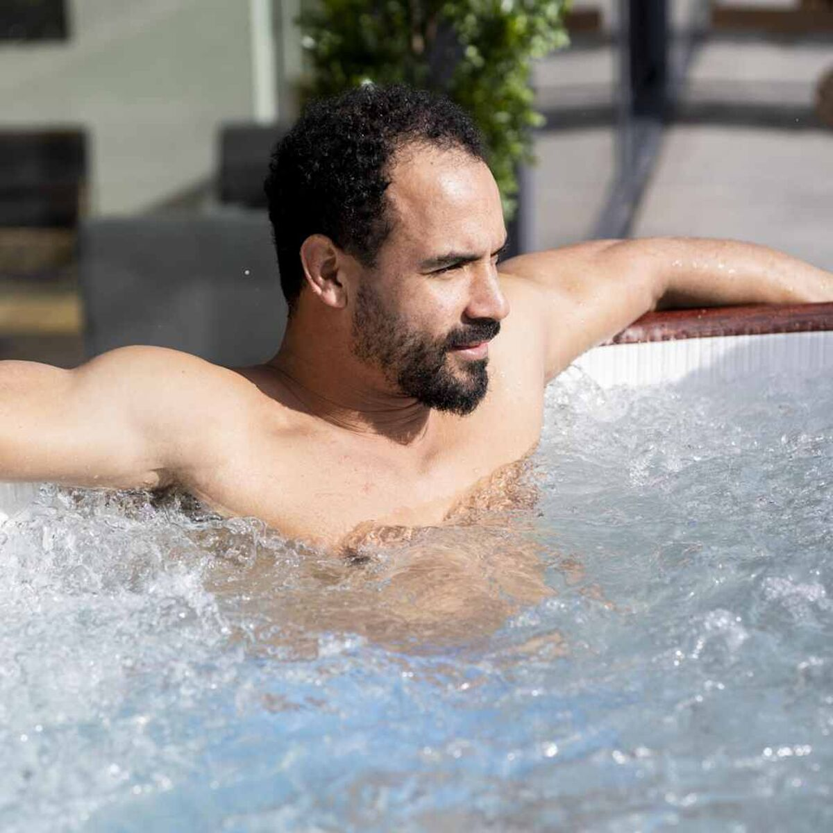 Ein Mann sitzt in einem Whirlpool. Wasser blubbert um ihn herum.