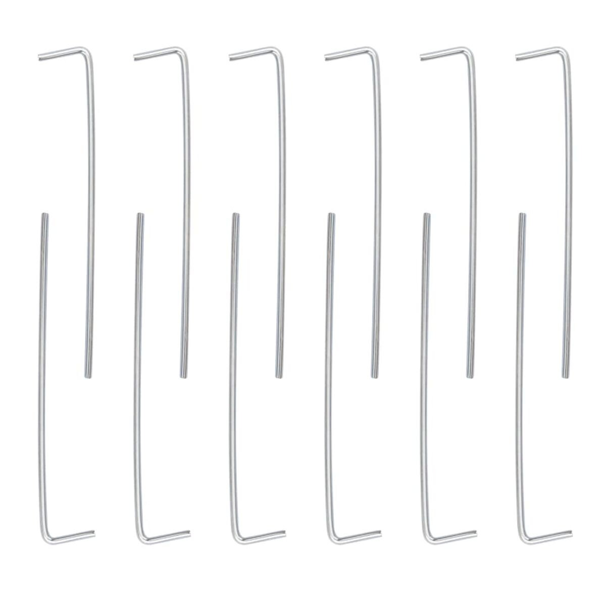 Eine Sammlung von Metall-Zeltpflöcken, gerade mit gebogener Spitze, in einem Rastermuster auf weißem Hintergrund angeordnet.