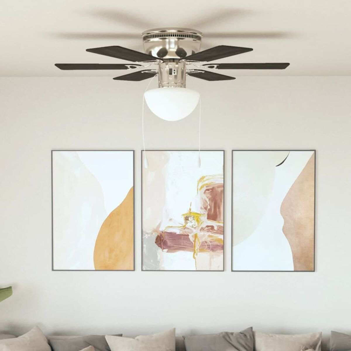 Un ventilatore a soffitto con 3 opere d'arte astratta sottostanti. Il ventilatore è argentato con pale scure.
