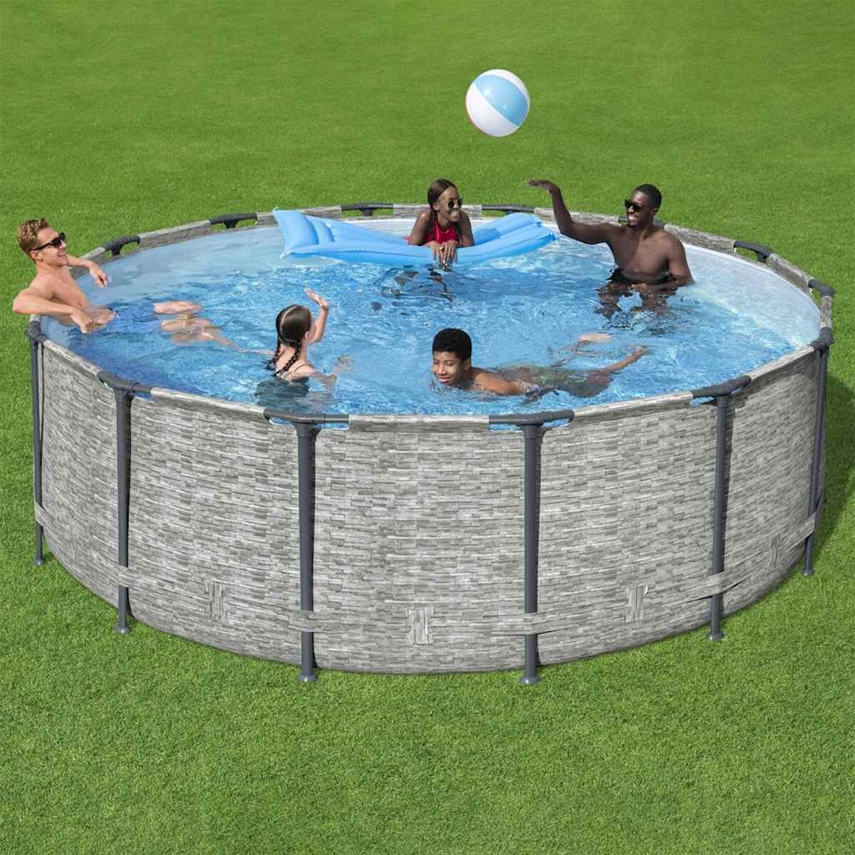 Menschen in einem runden Pool mit grauem, steinähnlichem Rand. Ein blau-weißer Ball ist in der Luft.