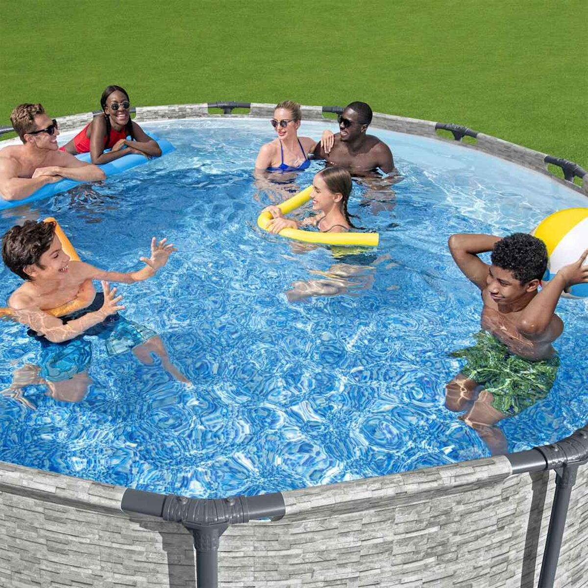 Eine Gruppe von Leuten in einem Pool. Sie spielen mit einem Ball und Schwimmnudeln.
