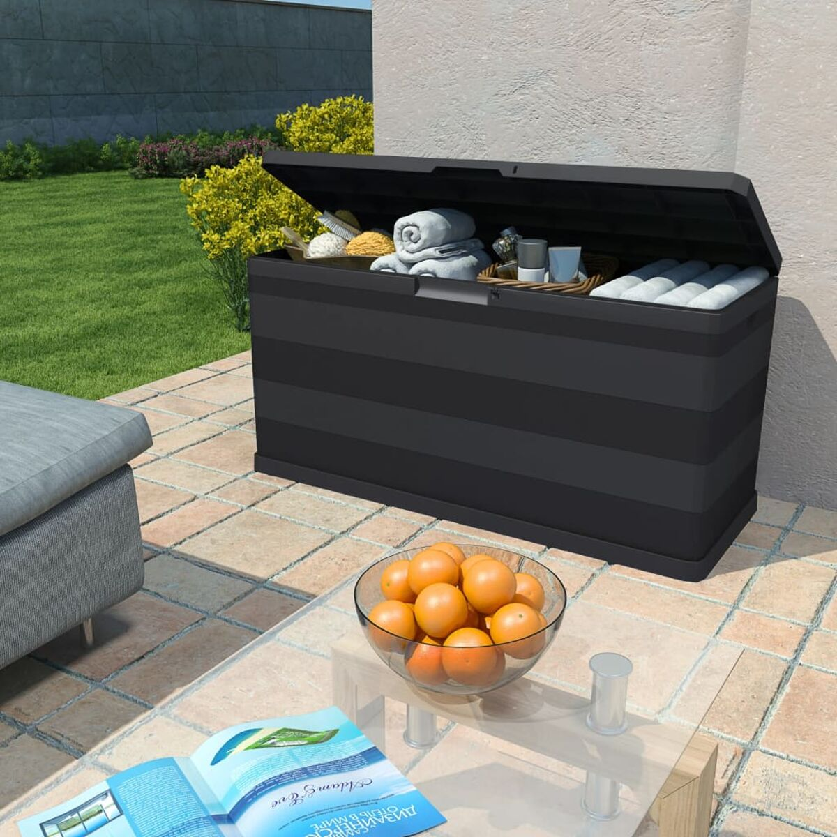 Eine schwarze Outdoor-Aufbewahrungsbox mit offenem Deckel, enthält Gegenstände und Orangen.