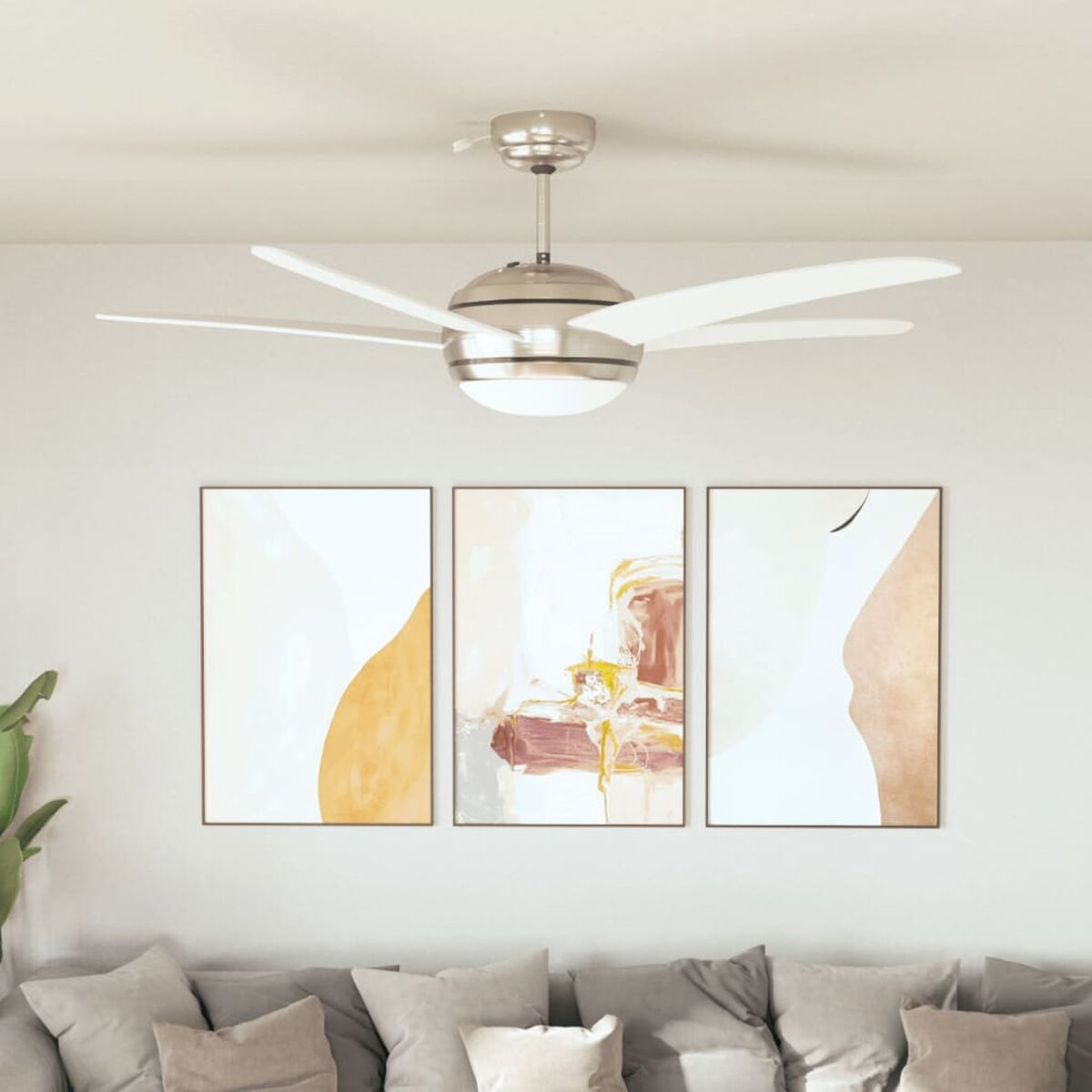 Un ventilatore a soffitto con 5 pale bianche, tre dipinti astratti e un divano grigio in una stanza.