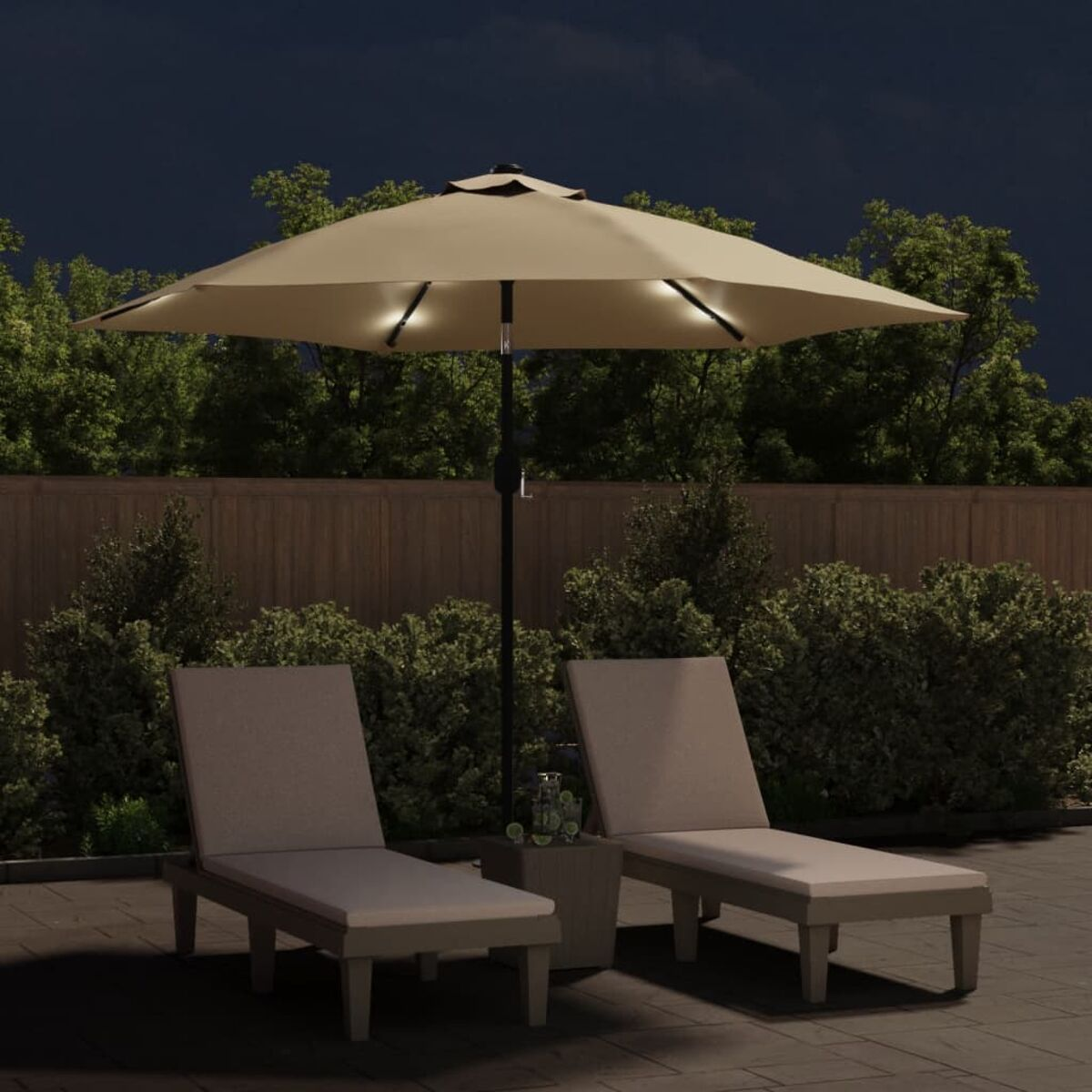 Eine beleuchtete Terrasse bei Nacht mit beigem Sonnenschirm, Stühlen und einem kleinen Tisch.