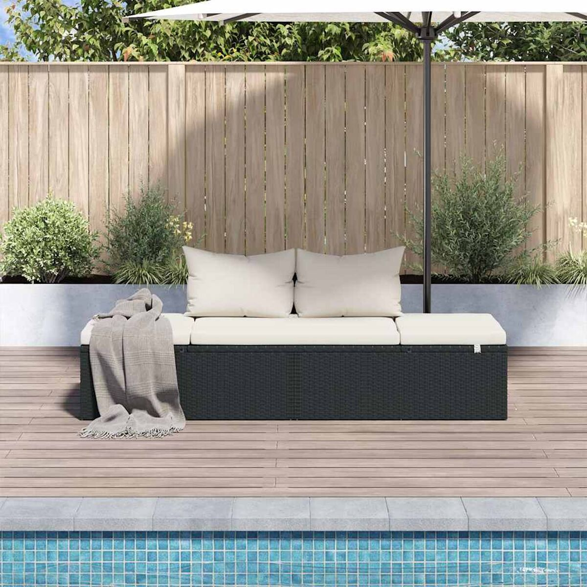 Outdoor-Sitzbereich mit dunkelgrauem Sofa, Kissen und Decke neben einem Pool.