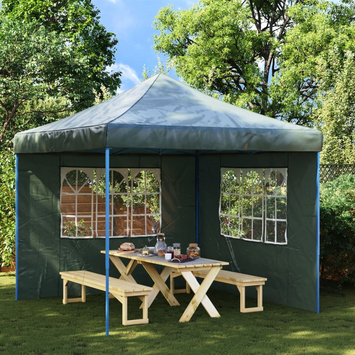 Ein grüner Outdoor-Pavillon mit Tisch und Bänken, auf einer Wiese.