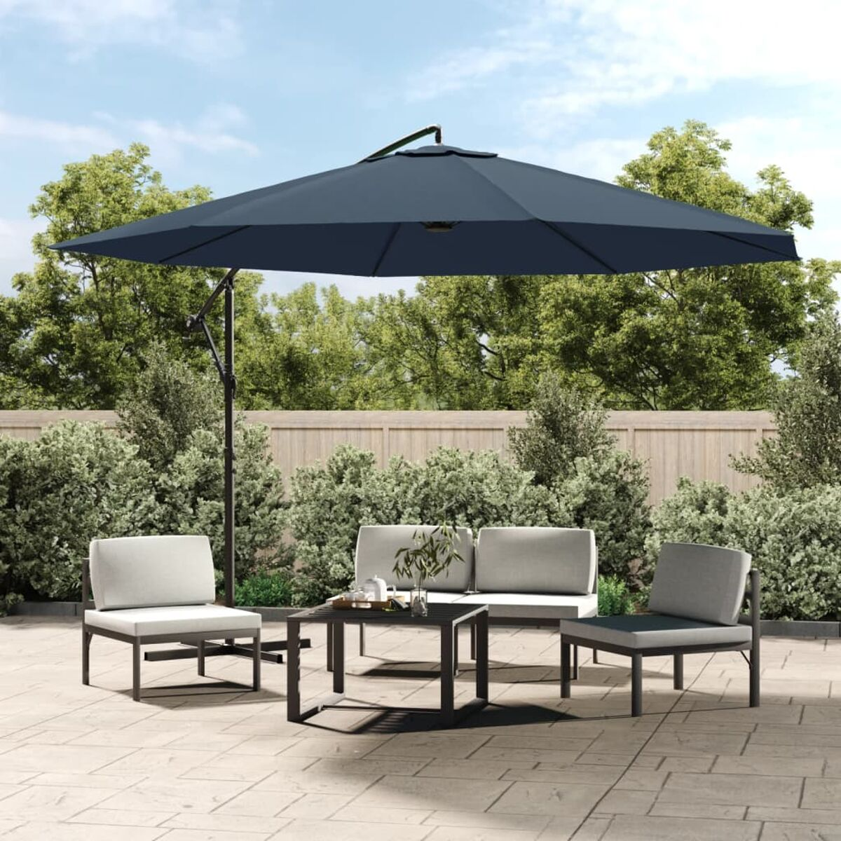 Outdoor-Terrasseneinrichtung mit großem Sonnenschirm, Tisch, Stühlen und grünem Hintergrund.