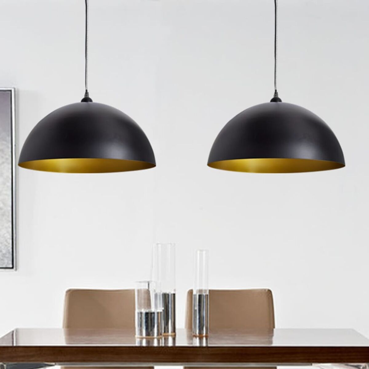 Zwei schwarze Pendelleuchten mit goldfarbenem Innenraum hängen über einem Tisch.