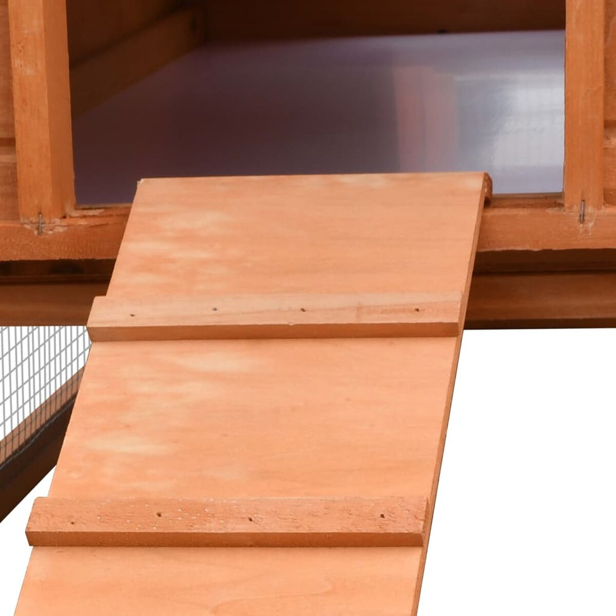 Eine Holzrampe, die in einen Hühnerstall aus Holz führt. Die Rampe hat Lamellen.