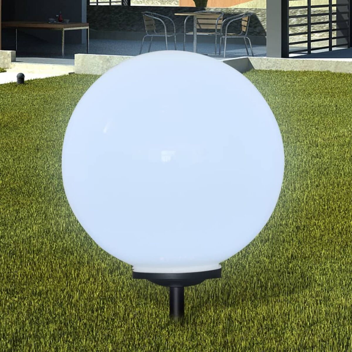 Eine weiße, kugelförmige Außenlampe auf einem schwarzen Ständer, auf grünem Gras.