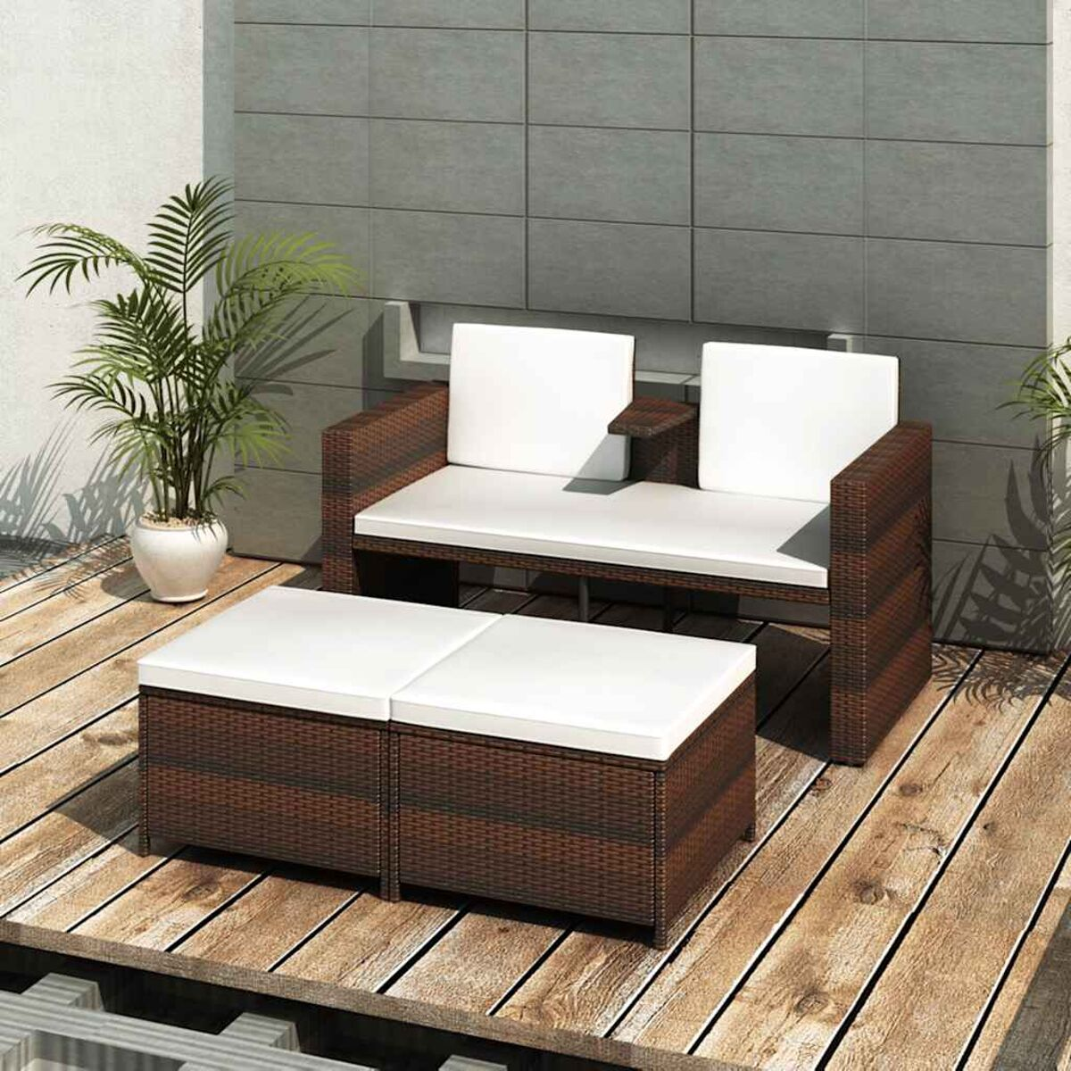 Terrassenmöbel: Ein braunes Korbmöbel-Sofa, zwei Ottomane und ein Beistelltisch. Weiße Kissen.