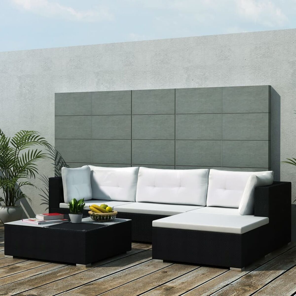 Outdoor-Sitzbereich mit Sofa, Couchtisch und Wand. Pflanzen und blauer Himmel sichtbar.