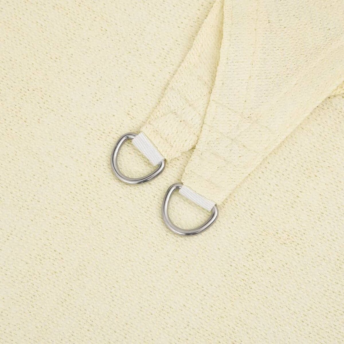 Nahaufnahme eines beigefarbenen Sonnensegels mit zwei D-Ringen zum Aufhängen.