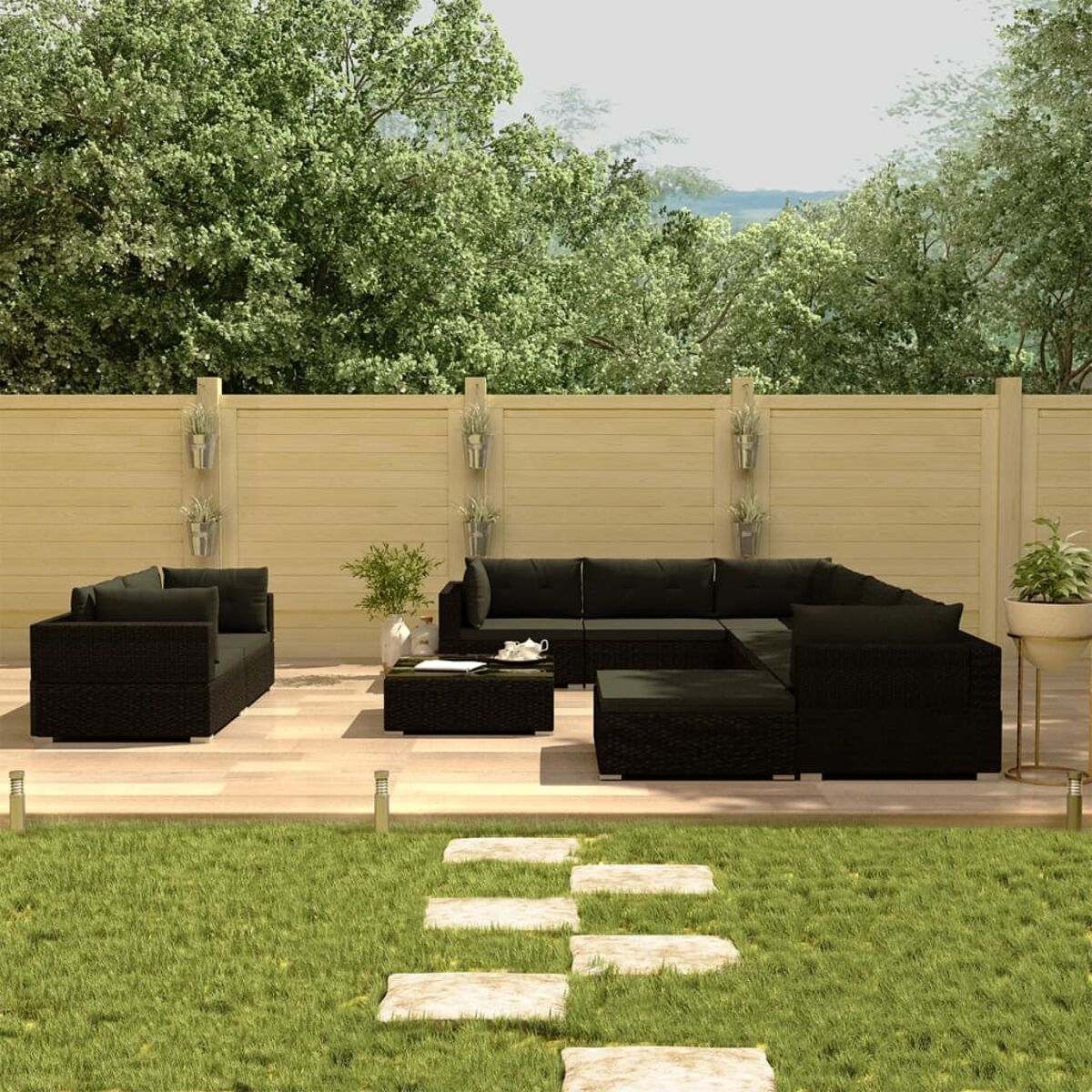 Schwarzes Gartenmöbel-Set. Sofa, Couchtisch und Pflanzen im Garten.