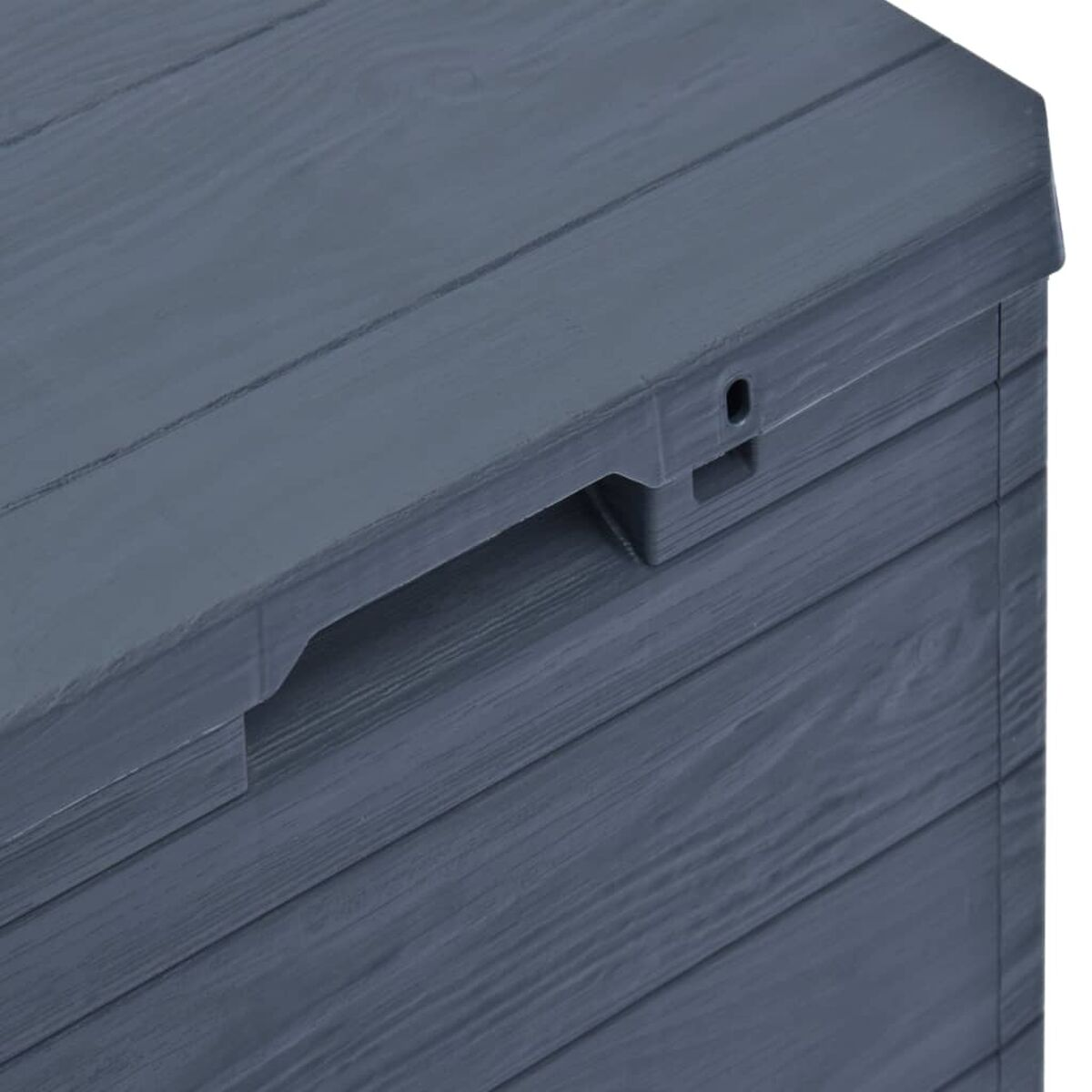 Nahaufnahme eines grauen Aufbewahrungsboxdeckels. Griffaussparung und Holzmaserung.