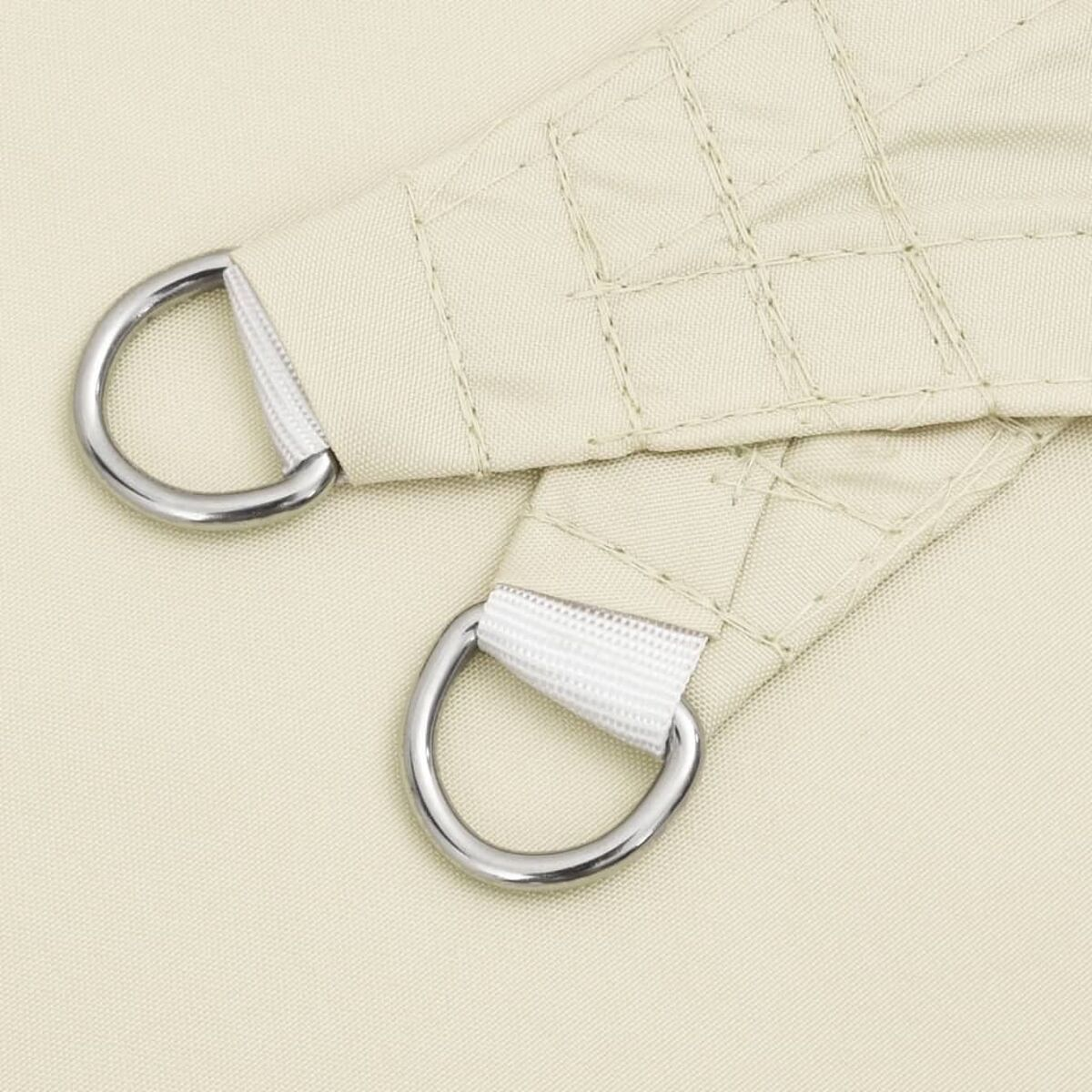 Nahaufnahme von beigem Stoff mit silbernen D-Ringen und weißem Gurtband.