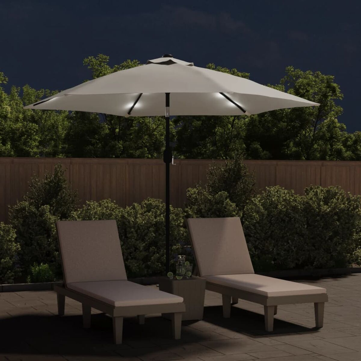 Terrasse bei Nacht mit Sonnenschirm, Stühlen und Lichtern. Bäume und ein Holzzaun im Hintergrund.