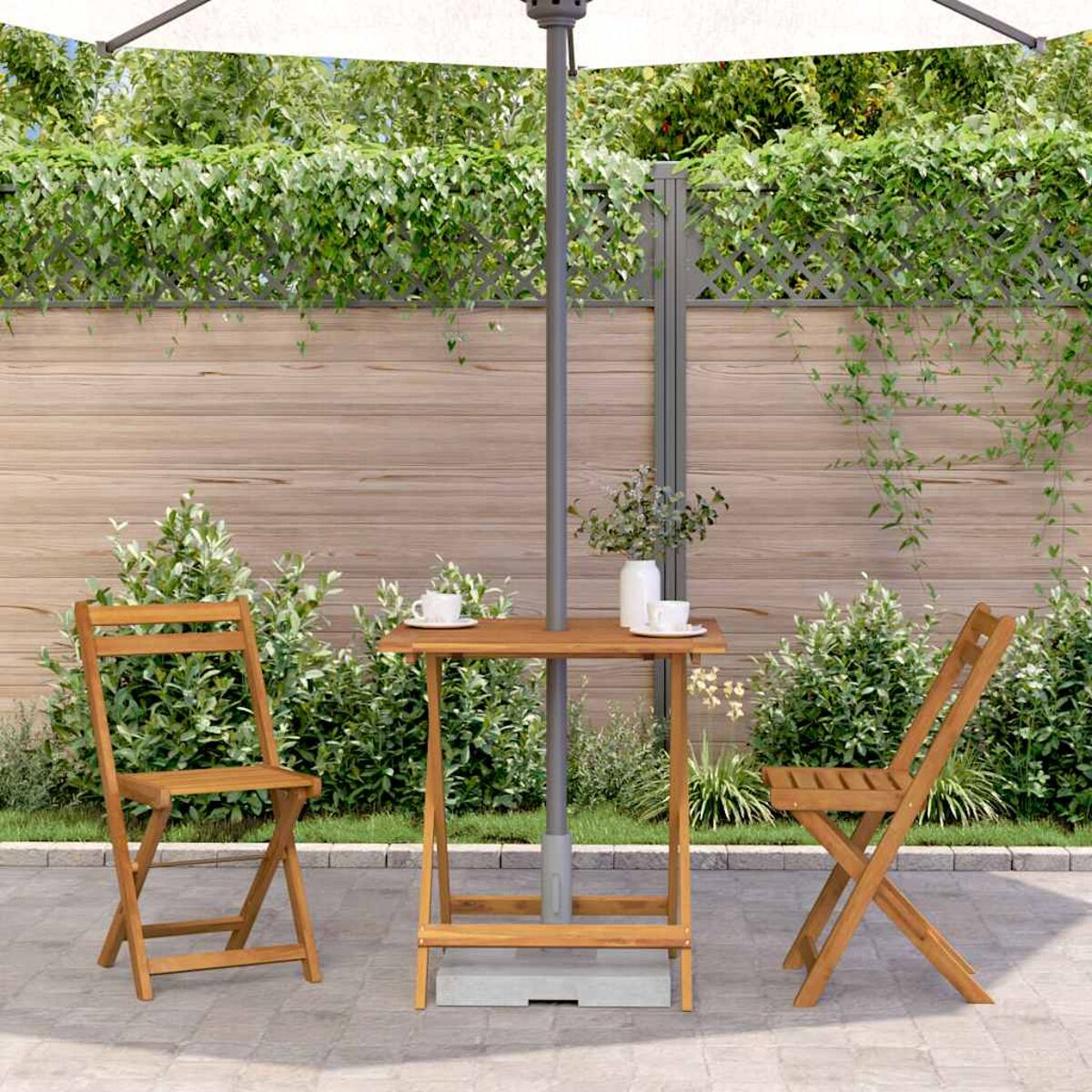 Ein Holztisch im Freien mit zwei Holzstühlen, unter einem Sonnenschirm in einem Garten.