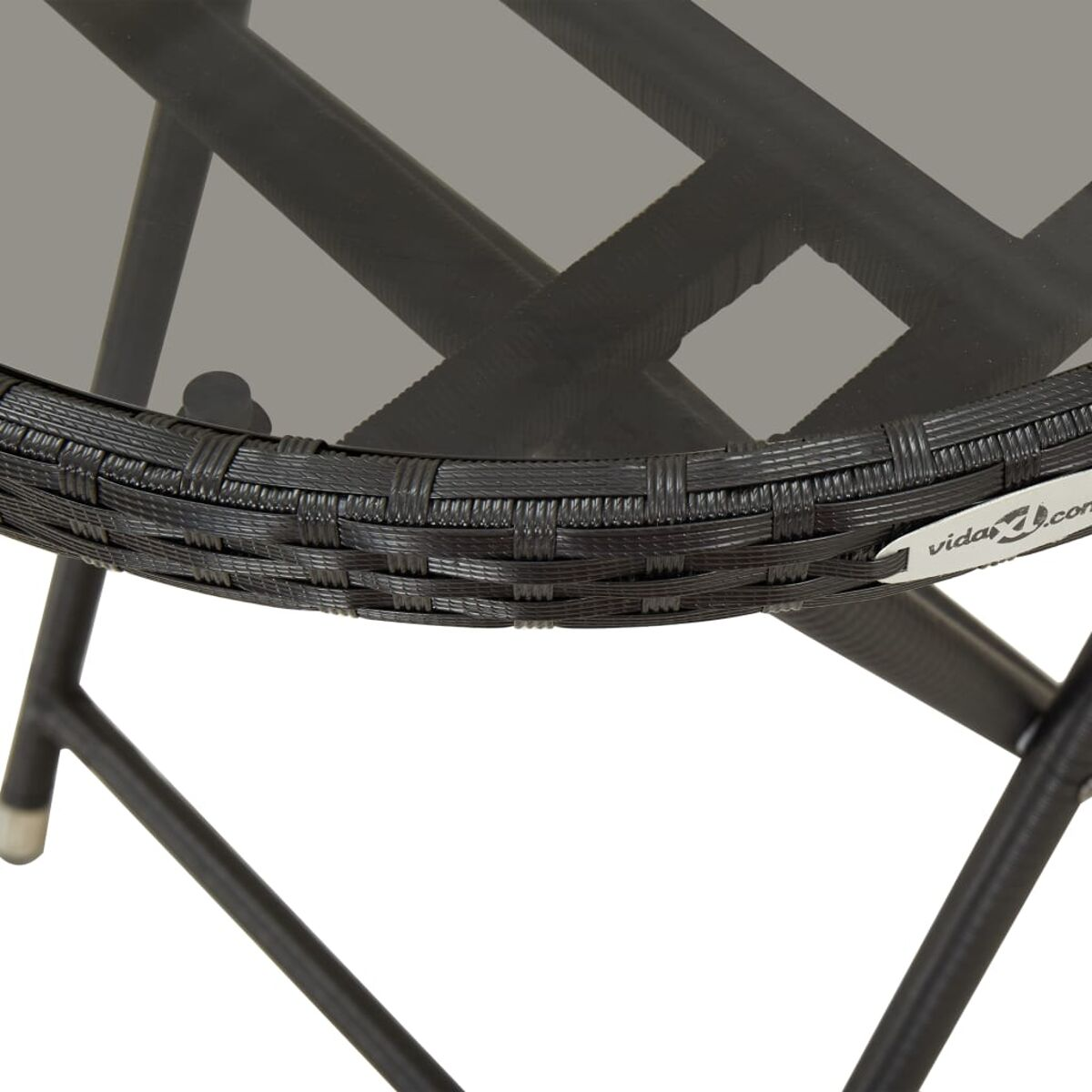 Nahaufnahme einer Tischkante. Schwarzes Korbgeflecht mit Glasplatte. vida.com-Logo sichtbar.