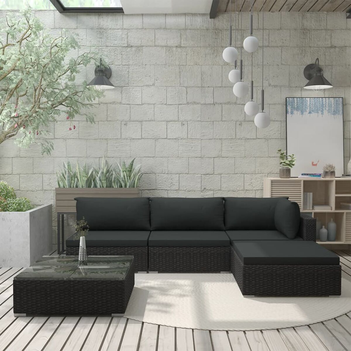 Outdoor-Terrasseneinrichtung mit dunkelgrauen Korbmöbeln, Teppich und Ziegelwand.