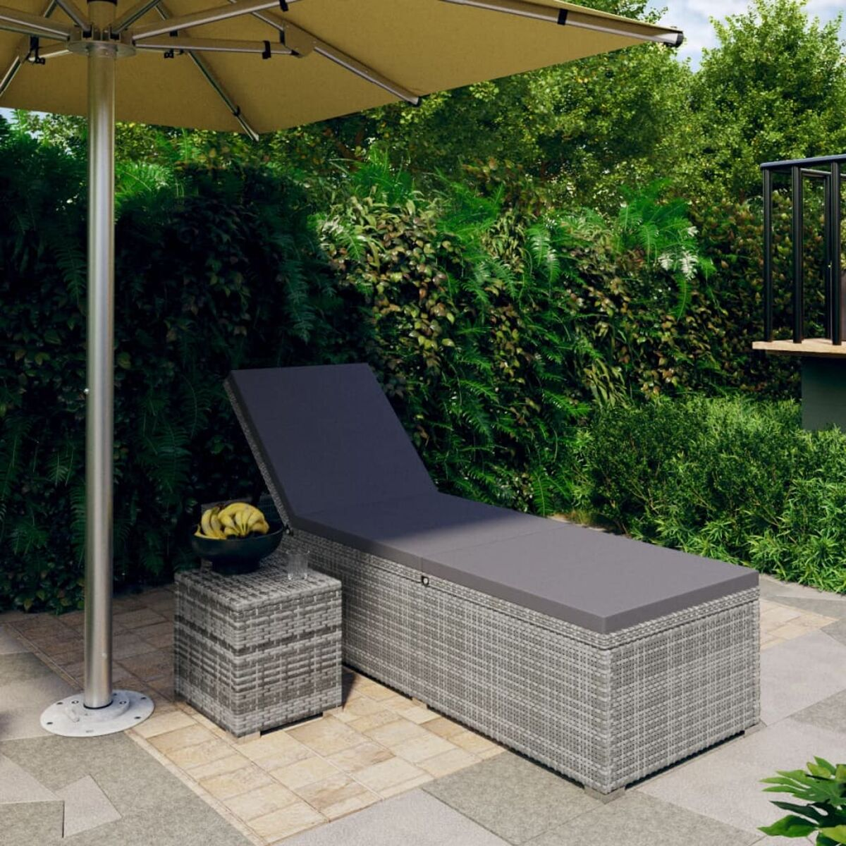 Graue Outdoor-Chaiselongue, kleiner Tisch mit einer Schale Bananen und gelber Sonnenschirm.