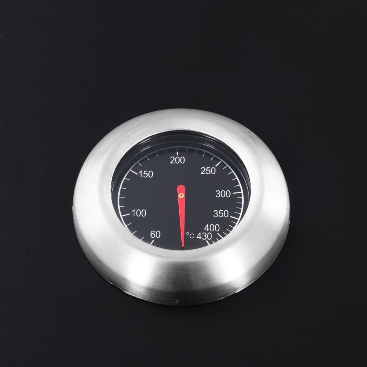 Ein rundes Thermometer mit roter Nadel. Schwarzer Hintergrund und Metallrahmen.