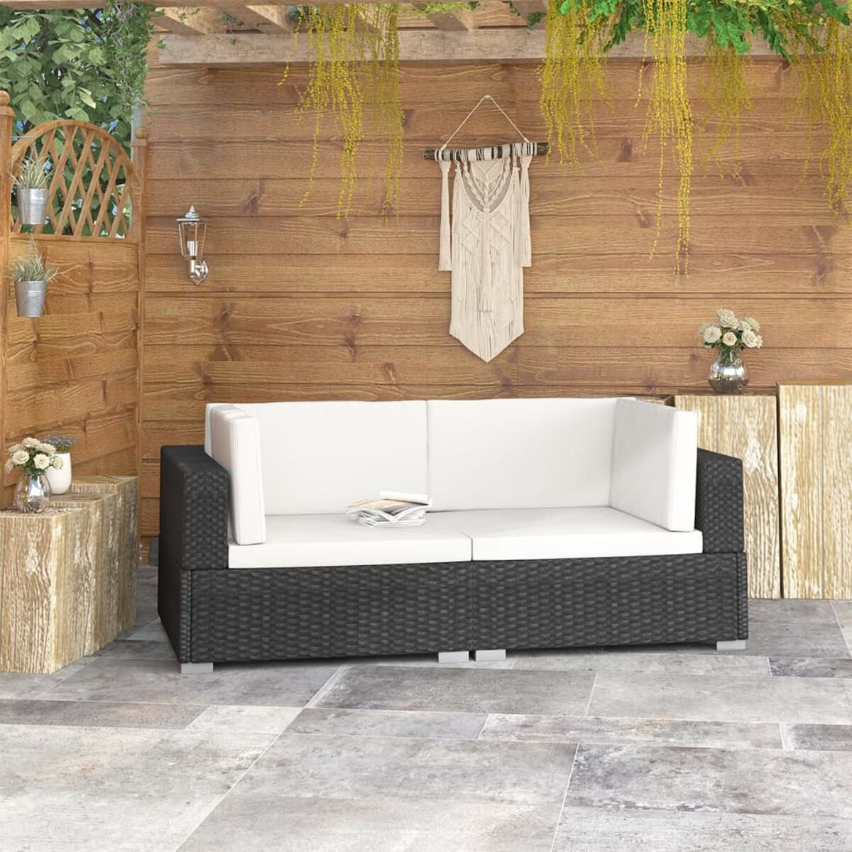 Schwarzes Korbmöbel mit weißen Kissen. Outdoor-Setting mit Holzwand und -boden.