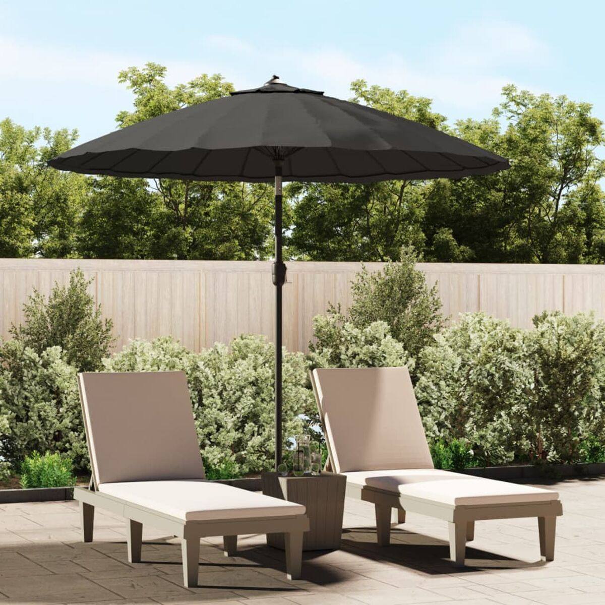 Ein schwarzer Sonnenschirm und zwei beige Liegestühle auf einer Terrasse mit Grün.