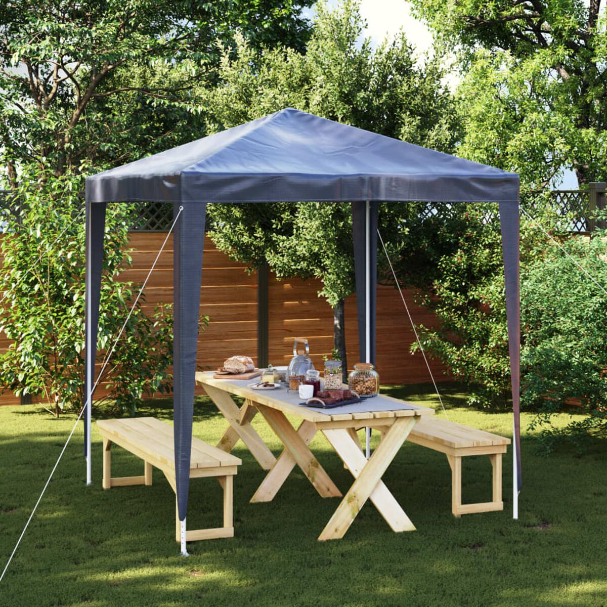 Ein Pavillon in einem Garten mit einem Picknicktisch, Bänken und Essen auf dem Tisch.