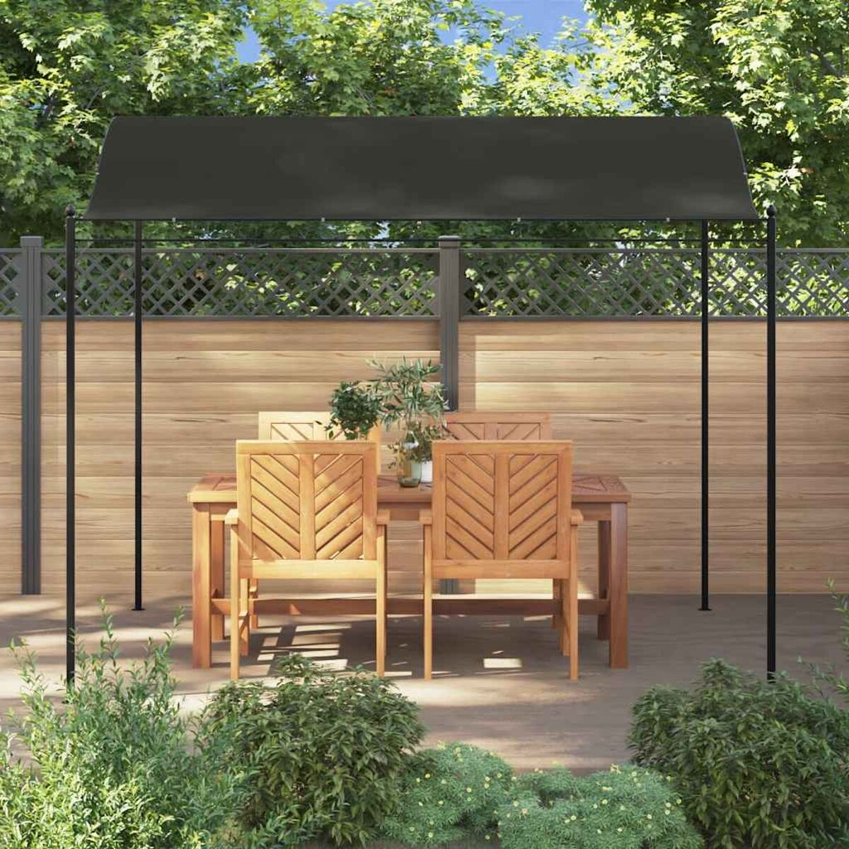 Terrassenset: Tisch, Stühle unter einem Baldachin. Holzzaun und Grün im Hintergrund.