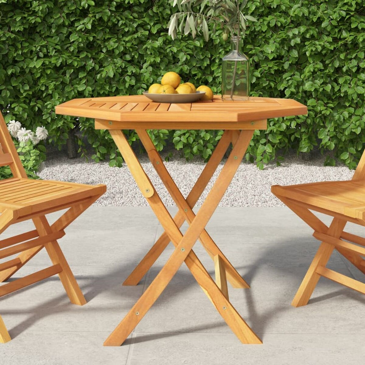 Holz-Achtecktisch und Stühle im Garten mit Zitronen und Grün im Hintergrund.