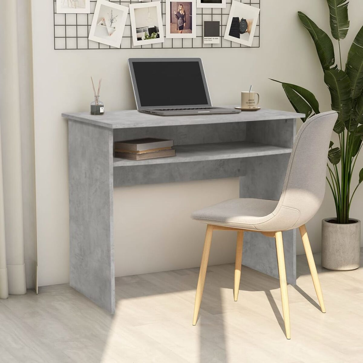 Grauer Schreibtisch mit Laptop, Büchern und Tasse. Ein Stuhl daneben.