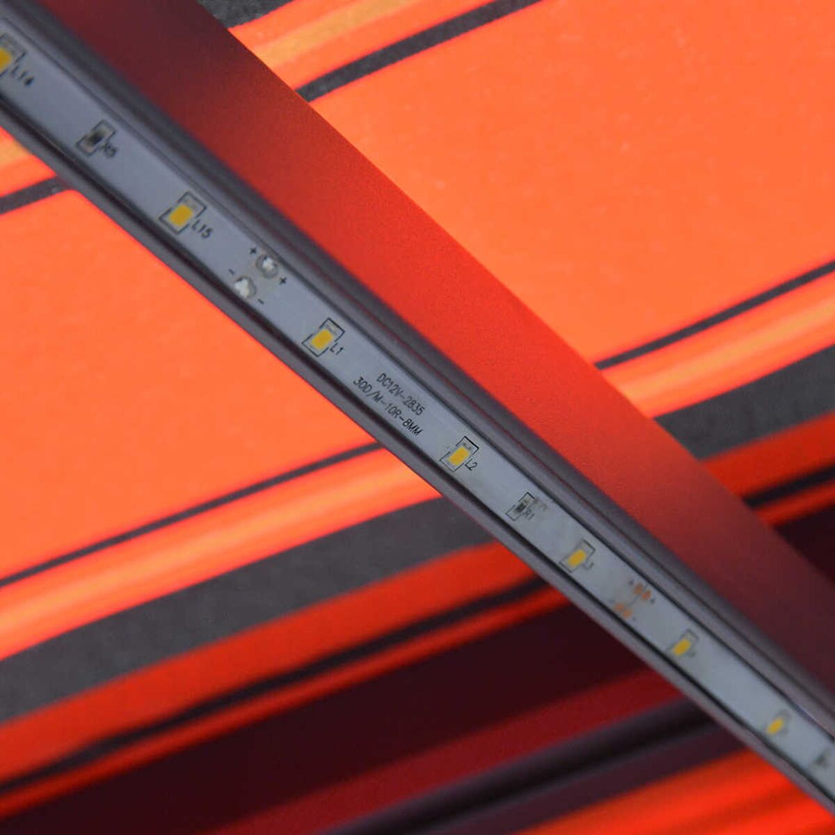 Rot-orange gestreifte Markise mit LED-Leuchten. Die LEDs sind an der Markise montiert.
