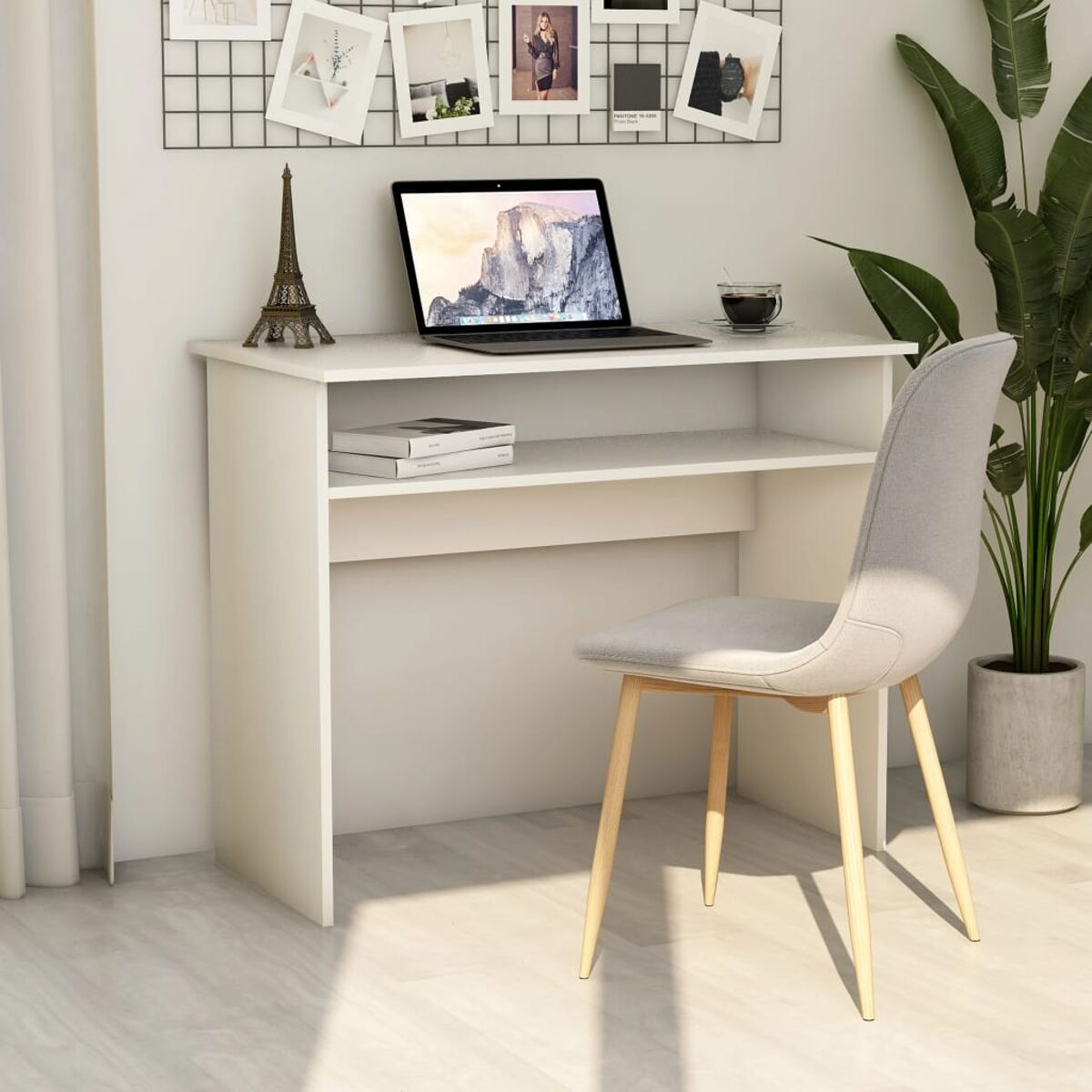 Ein weißer Schreibtisch mit Laptop, Büchern und einer Kaffeetasse. Ein Stuhl steht daneben.