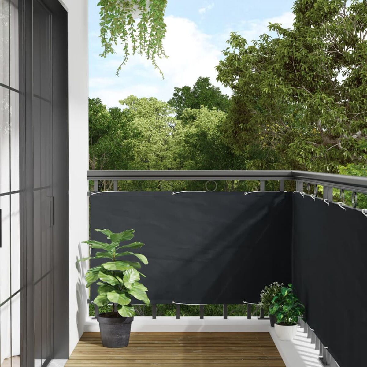 Balkon mit schwarzem Sichtschutz, Pflanzen in Töpfen, Holzboden, Bäumen im Hintergrund und Himmel.