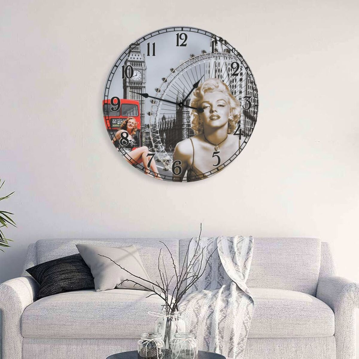 Un orologio rotondo con l'immagine di Marilyn Monroe. Mostra i monumenti di Londra. Parete bianca, divano grigio e decorazioni.