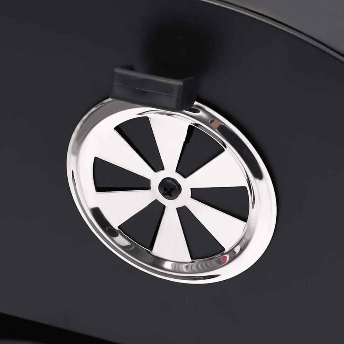 Zbliżenie otworu wentylacyjnego grilla na czarnym tle. Otwór jest srebrny.