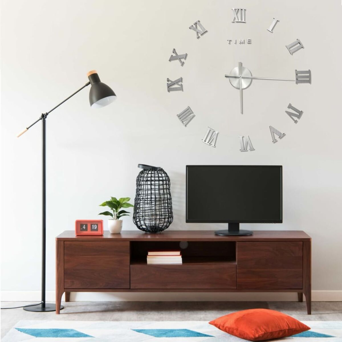 Wohnzimmer mit Fernseher auf einem Holzschrank. Uhr und Pflanze an der Wand.