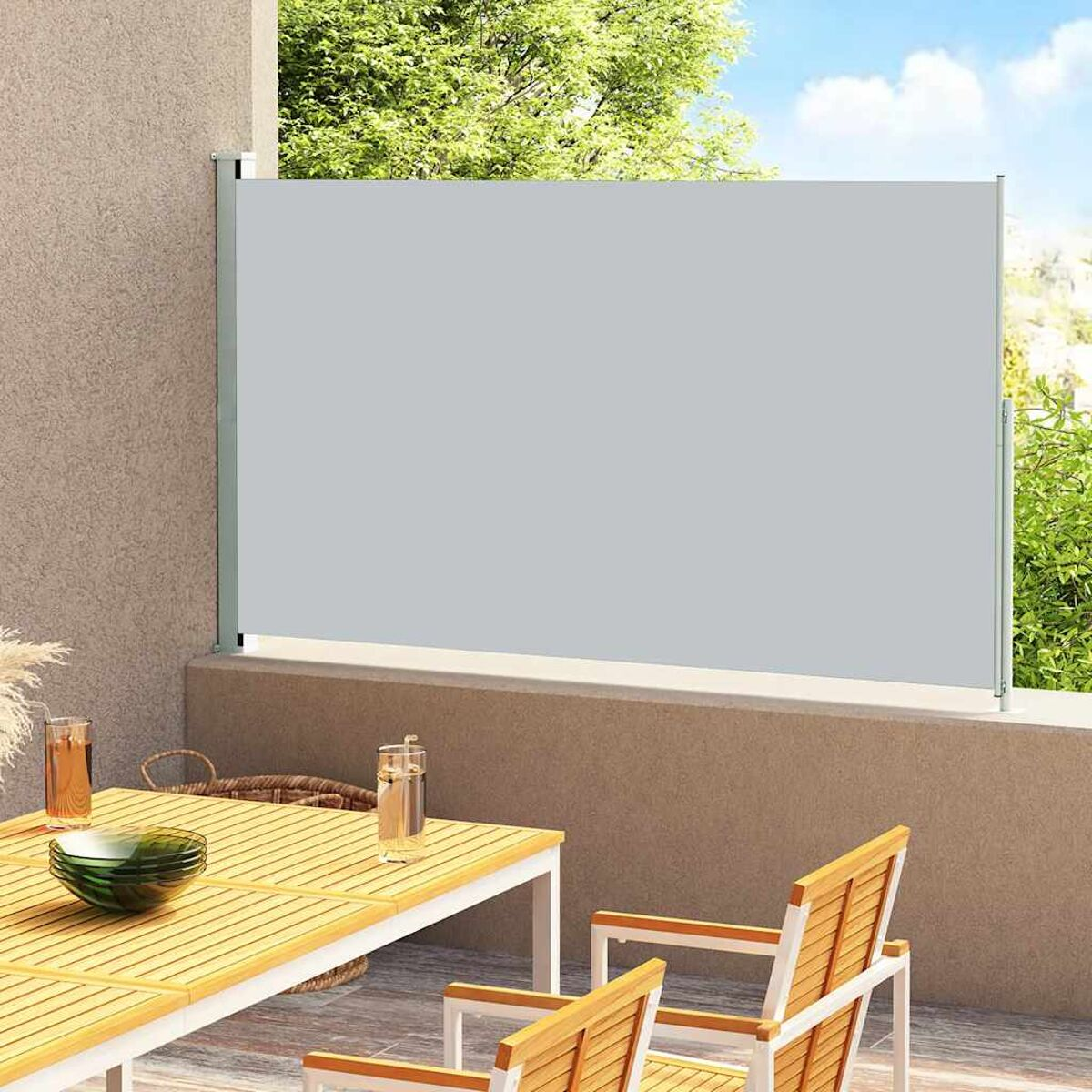 Grauer Outdoor-Sichtschutz auf einer Terrasse mit Tisch und Stühlen, grüne Pflanzen.